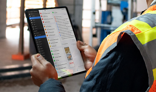 Construction worker checks Fieldwire projects on an ipad on the jobsite 