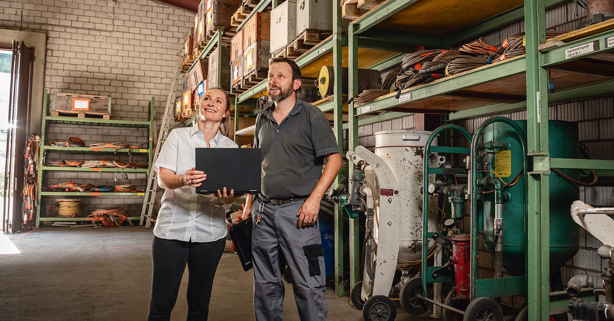 Two people in warehouse with a computer